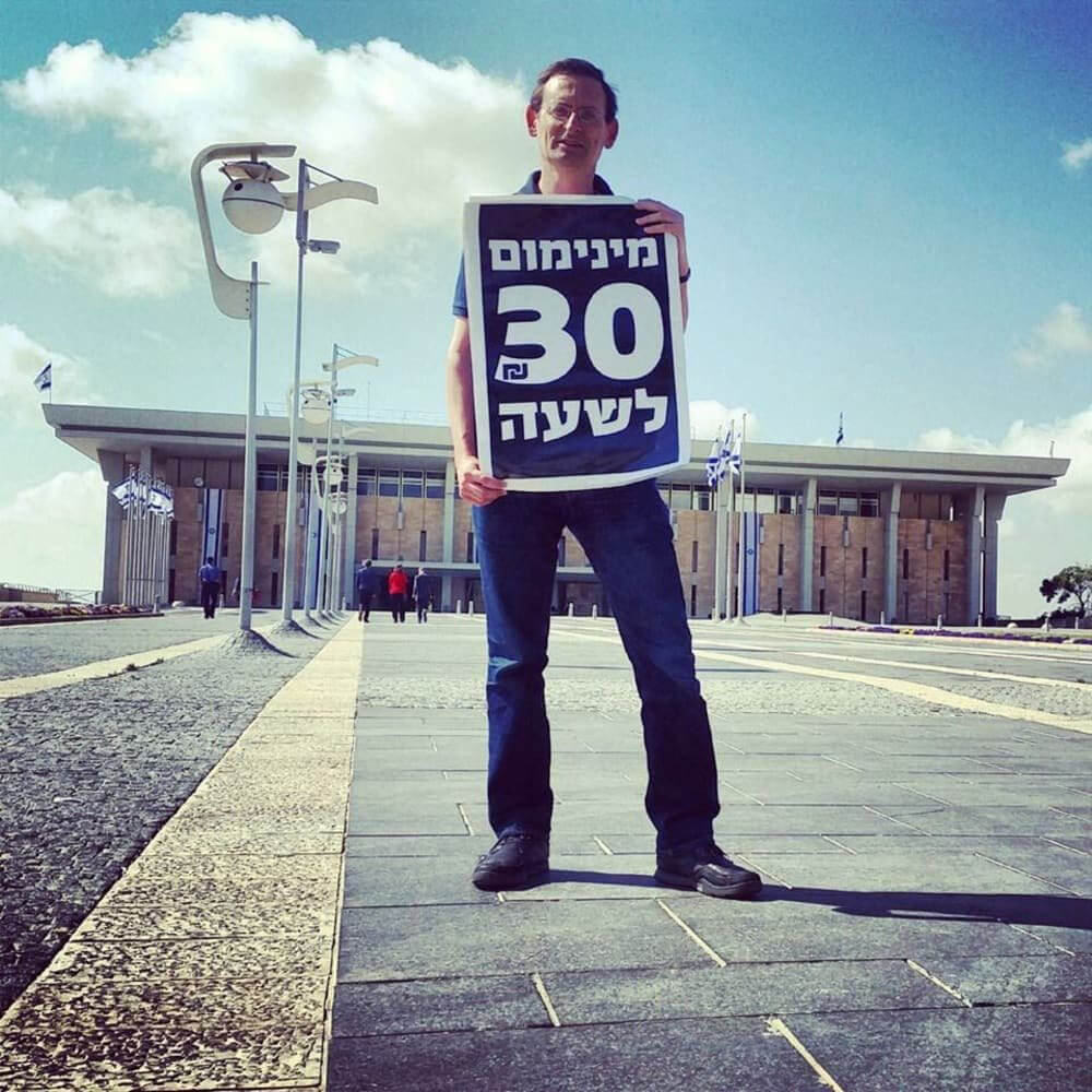 Khenin während des Kampfs um die Anhebung des Mindestlohns. Auf dem Plakat steht: „Mindestens 30 Schekel pro Stunde“. Foto: Alon Lee Green