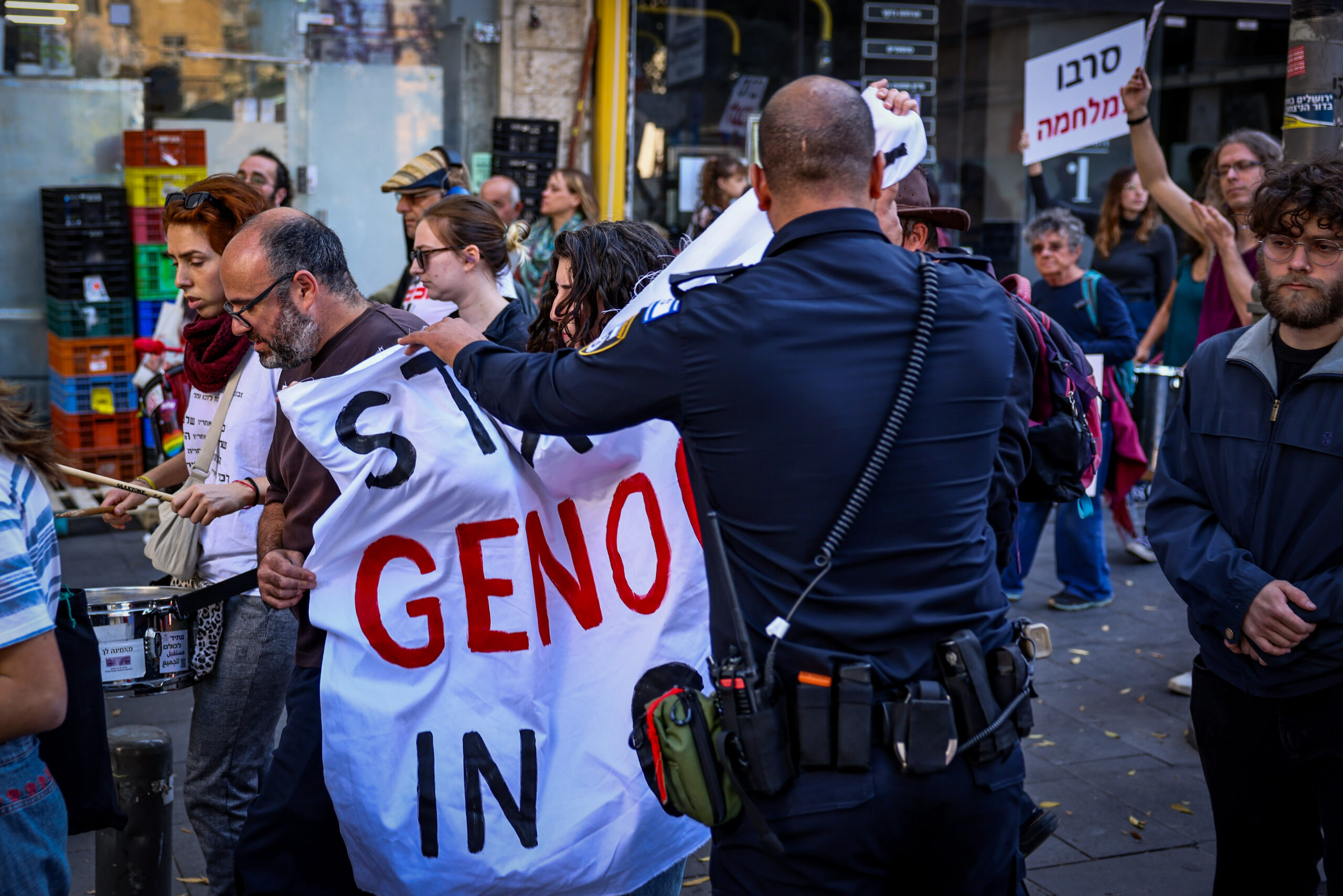 Ein israelischer Polizist konfisziert ein gegen Genozid gerichtetes Banner auf einem linken Protestmarsch gegen den Krieg in Gaza; Jerusalem, 22. November 2024. Foto: Flash90