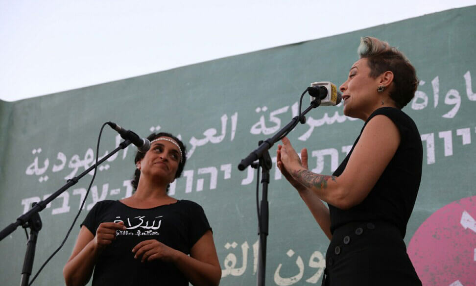 Die jüdische Israelin Achinoam Nini und die palästinensische Israelin Mira Awad am 30. Juli 2018 auf dem Habima-Platz im Zentrum von Tel Aviv. Die beiden Sängerinnen beteiligten sich am öffentlich abgehaltenen Arabischunterricht, der sich gegen die Herabstufung der arabischen Sprache wendete. Foto: Activestills