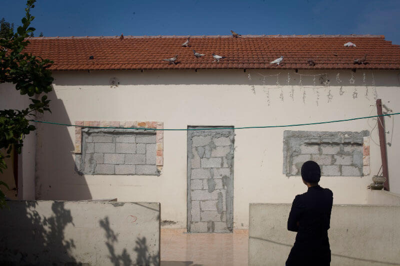 Eine Frau der al-Aju Familie betrachtet eines der Häuser, die von den israelischen Behörden zugemauert wurden, Ramle, Israel, 2011. – Der Gebäudekomplex, in dem acht Familien leben, befindet sich auf Land im Besitz von Amidar Public Housing (eine für Sozialwohnungen zuständige öffentliche Körperschaft, die u.a. von „Abwesenden“ enteigneten Grundbesitz verwaltet). Amidar behauptet, dass die Familien dort illegal leben. Bei den Familien handelt es sich ursprünglich um Flüchtlinge aus Lod (Lydda), die sich nach ihrer Vertreibung im Jahr 1948 in Ramle niederliessen. (Foto: Activestills)