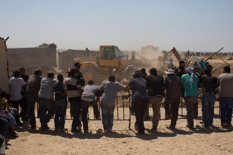  Zerstörung des Dorfes al-Araqib, Negev, Israel, 12.6.2014. (Foto. Activestills) – Beduinen schauen der Zerstörung ihres Dorfes zu. Die israelischen Behördern haben das Dorf seit 2010 über 100-mal abgerissen.