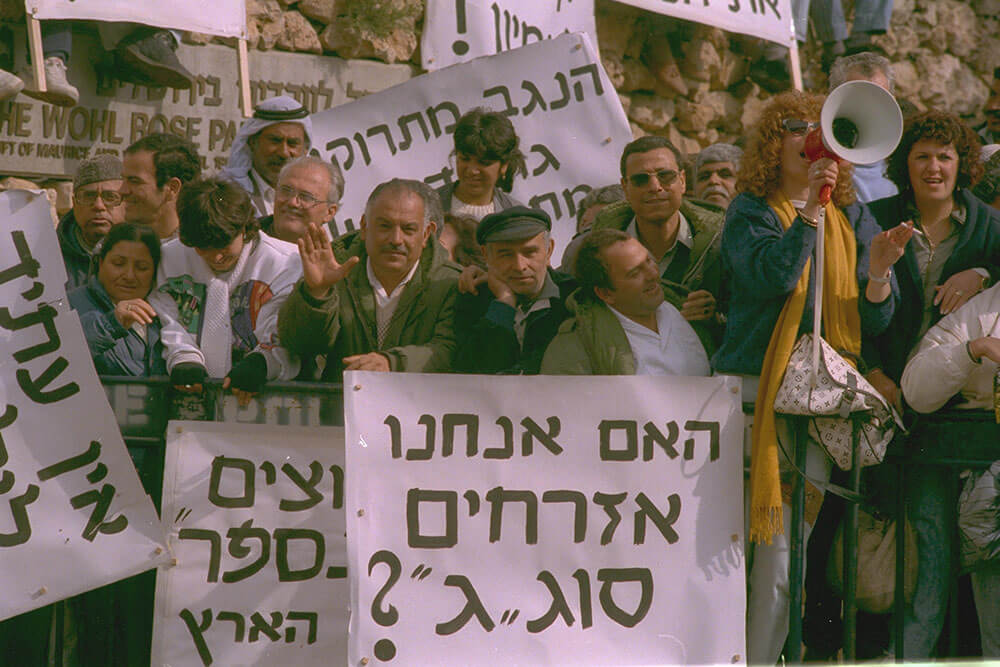 Arbeitslose Arbeiter*innen aus Dimona, einer "Entwicklungsstadt" im Negev demonstrieren vor der Knesset. (auf dem Schild steht: "Sind wir Bügrer dritter Klasse?")1988